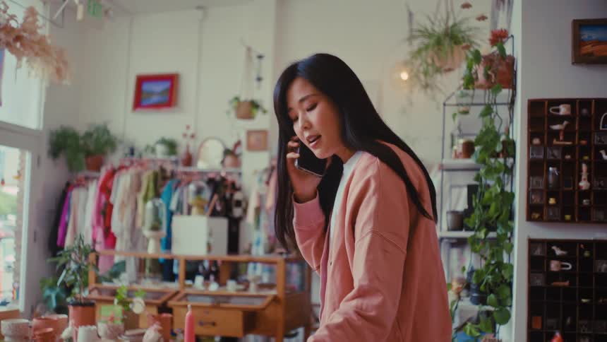A woman talks on a smartphone while working in a boutique