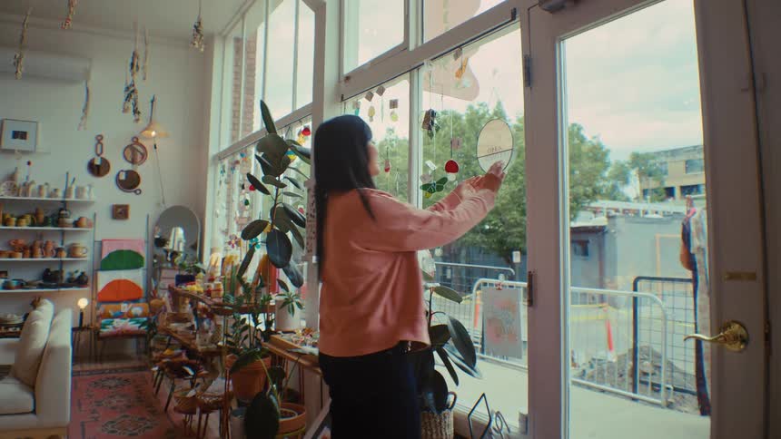 A woman flips a sign on the glass door of a boutique