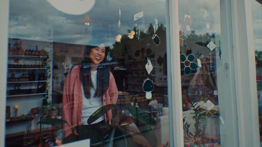 Woman standing inside a store waving to someone in the window
