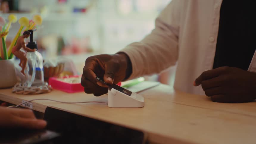 Contactless payment is made with a card over a terminal on a shop counter