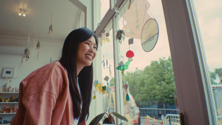 Woman places an open shop sign on the glass door of the store