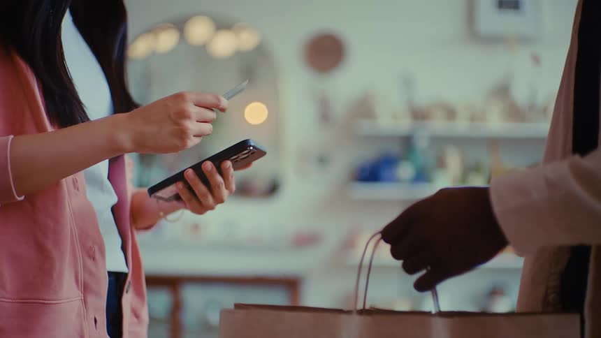 Man hands a card for payment to a clerk at a shop counter