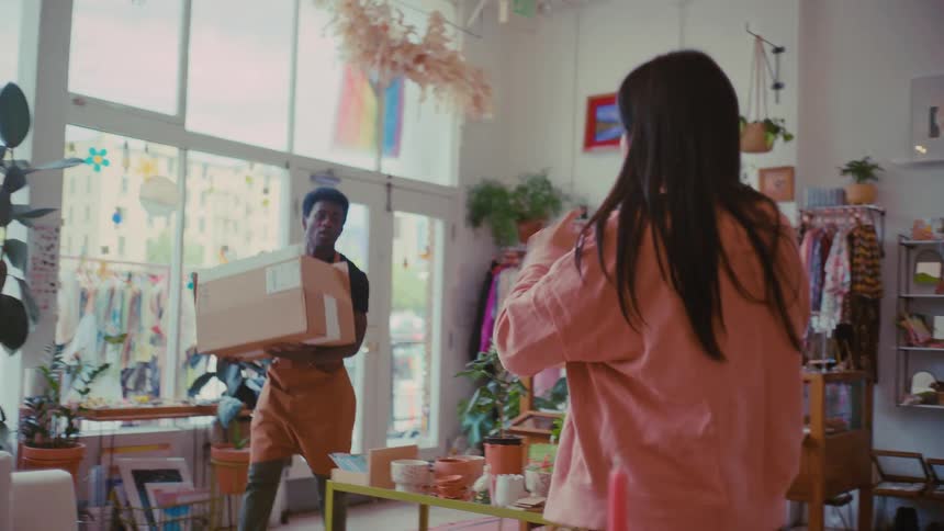 Man enters a clothing store with a box while a woman is on a phone call