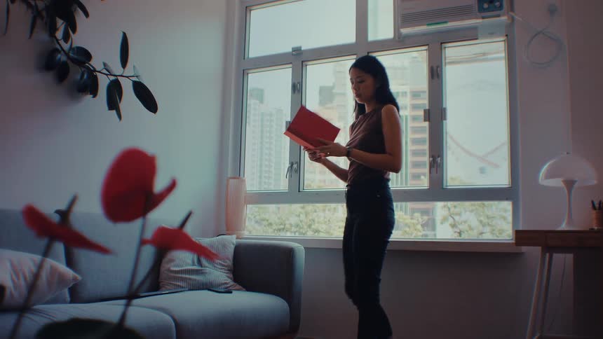 The woman reading a book checks her watch and runs out of the room
