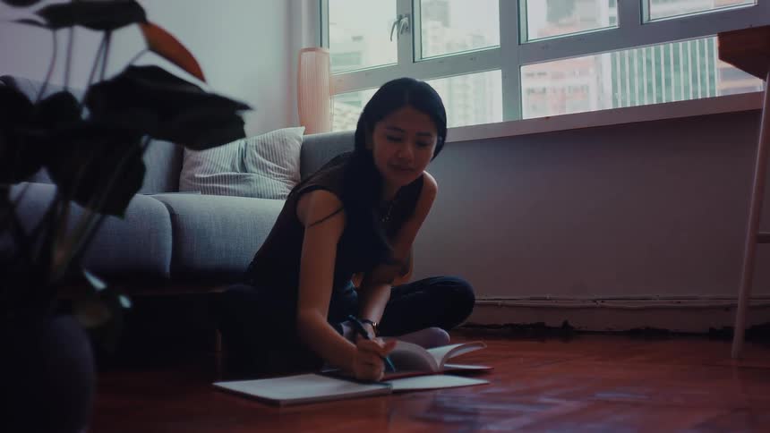 Teenage girl sitting on the living room floor doing her homework