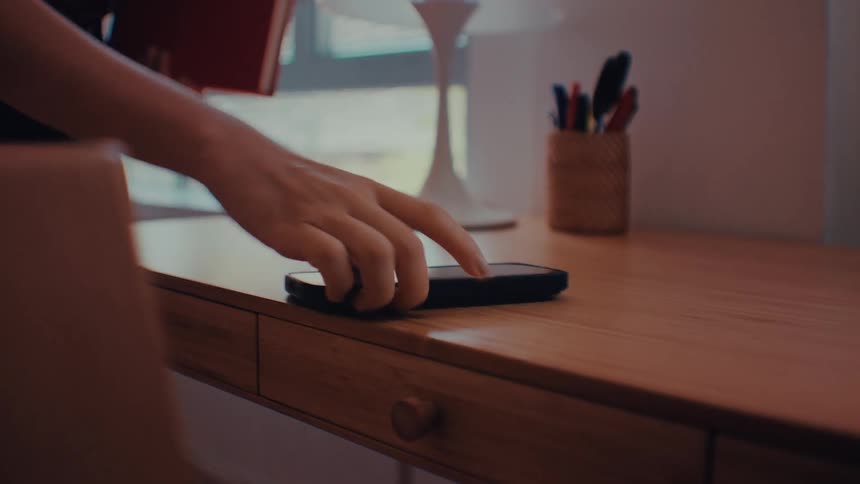 A person picks their phone up off a desk