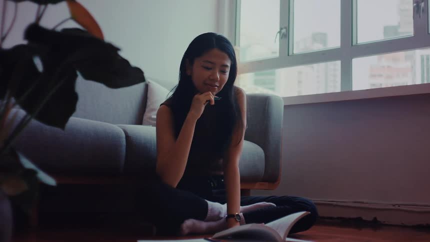 Teenage girl sitting on the living room floor doing her homework