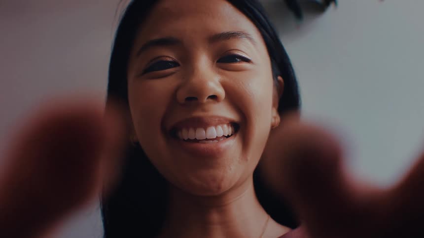 Womans face smiles in an indoor setting with a neutral blurred background