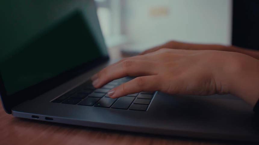 Girls hands and fingers typing on the keyboard of a laptop computer