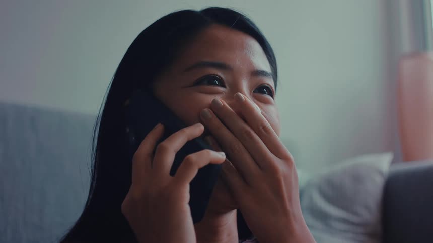 The woman is smiling and talking on her cell phone