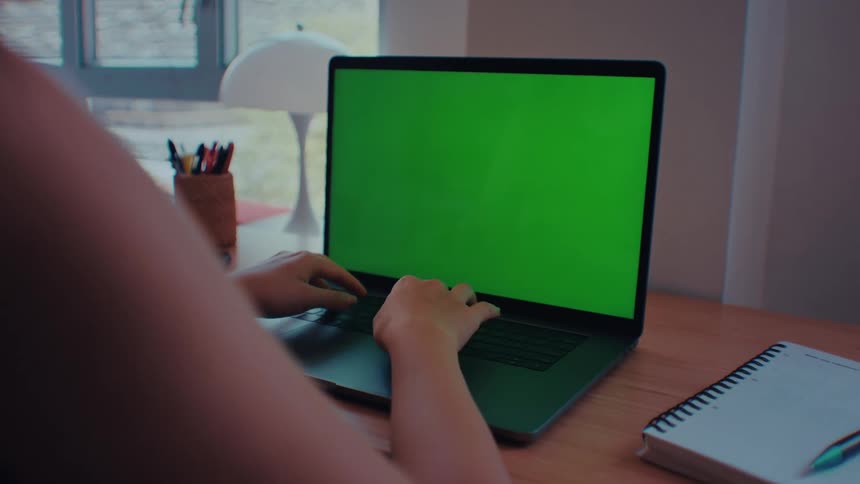 A woman sitting behind a desk in an office focused as she types on her laptop computer the workspace around her neat and professional