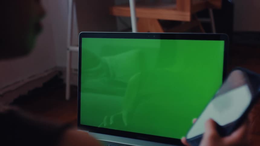 Person typing on a laptop and answering a call on a smartphone