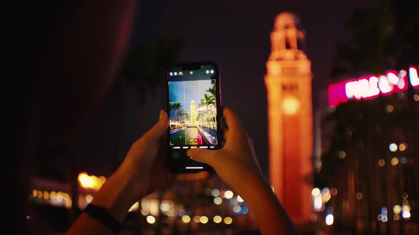 A person taking a photo of a tower outdoors at night