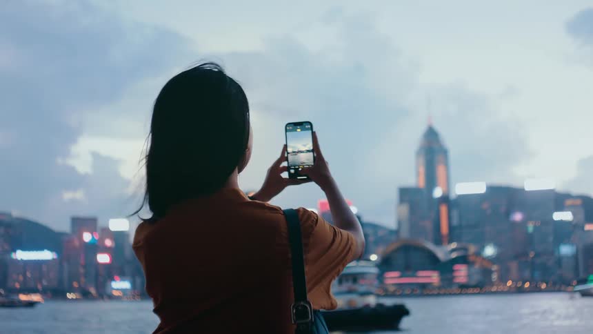 A woman taking pictures of a building with a smartphone