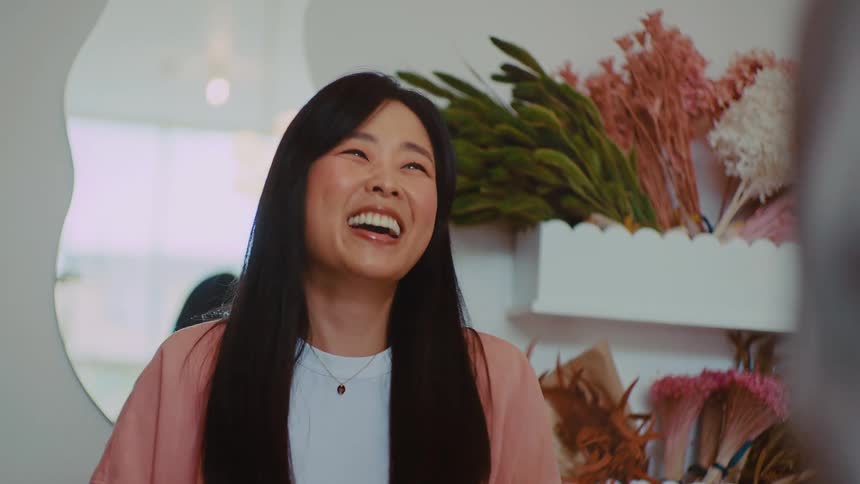 Smiling woman is talking to another person and receiving a book