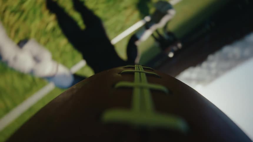 A pov shot shows a spinning football flying through the air on a field