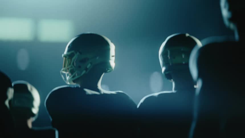 Football team standing next to each other on a stadium outdoors during night time
