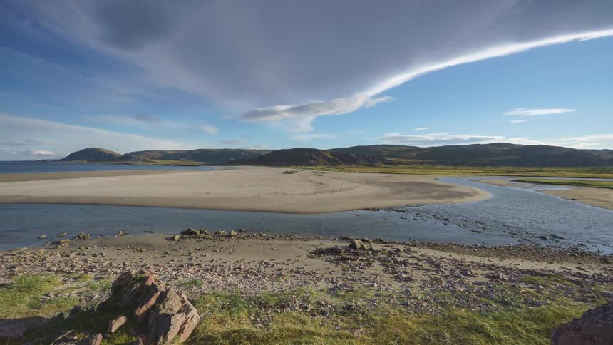 A winding river flows through a rocky and grassy landscape under a cloudy sky