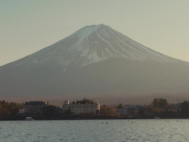 Peaceful view of mount fuji at sunset with lake and city at the mountains base