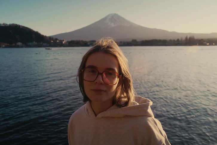 The woman is standing by the large lake