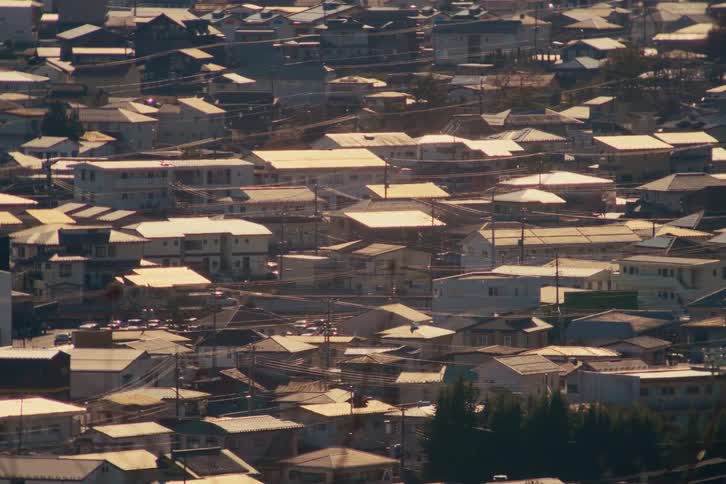 A sunlit view of a closely packed houses and small apartment buildings in a neighborhood