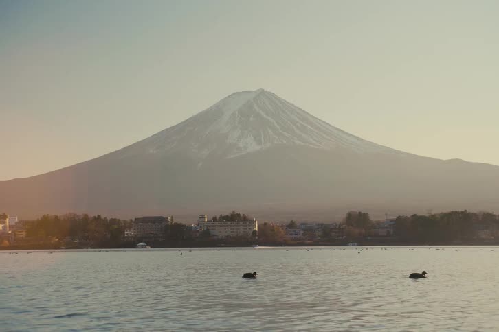 River next to a small city with a mountain on the background
