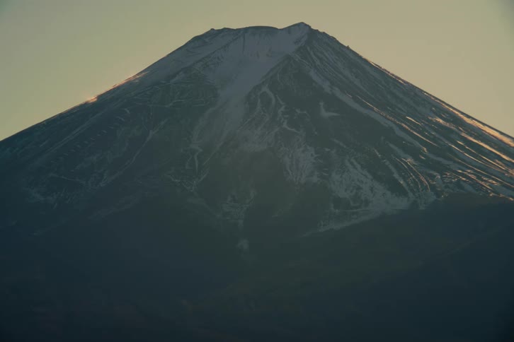 Snow on the rough terrain of a mountain under a hazy sky
