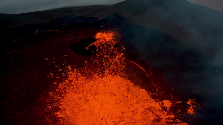 Dark smoke floats above an erupting volcano on a cloudy day