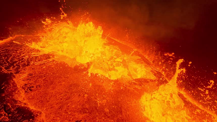 Glowing hot lava bubbles and erupts from a volcano at nighttime