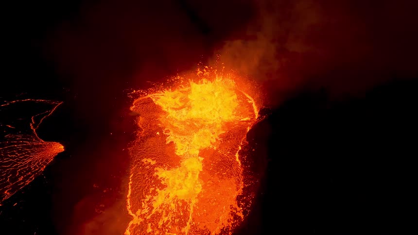 Smoke hovers over an erupting volcano at night