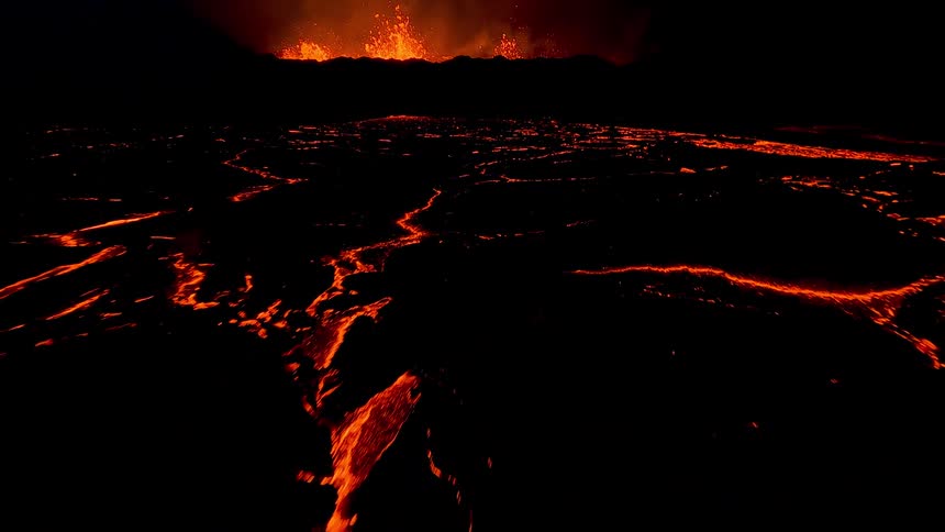 Volcanic eruption with glowing lava spreading and intense flames under a dark sky