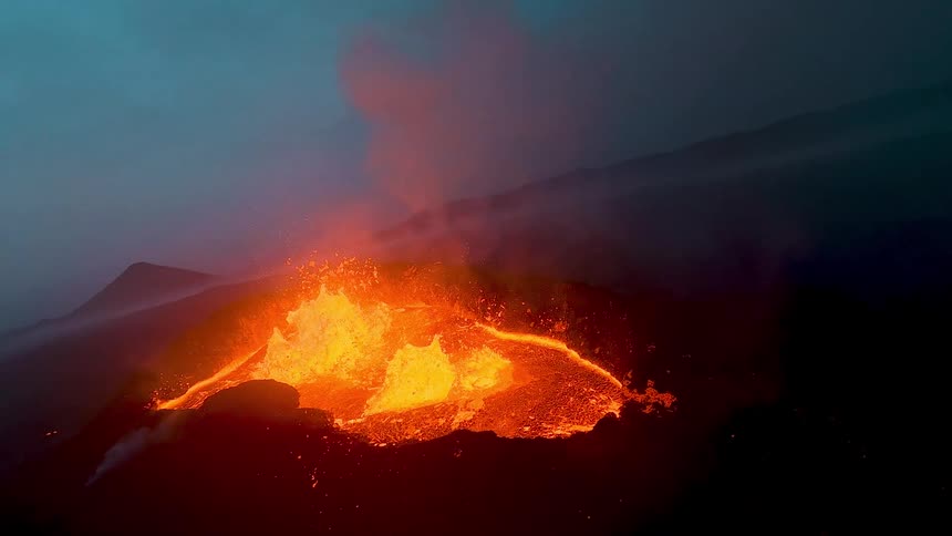 Glowing lava streams down a dark volcanic slope during nighttime eruptive activity