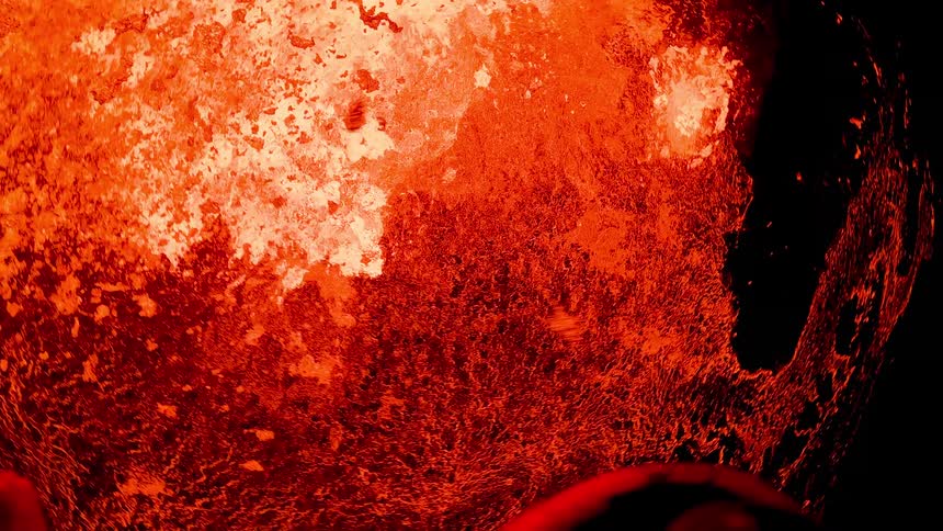 Hot molten lava glows as it flies into the air from an erupting volcano