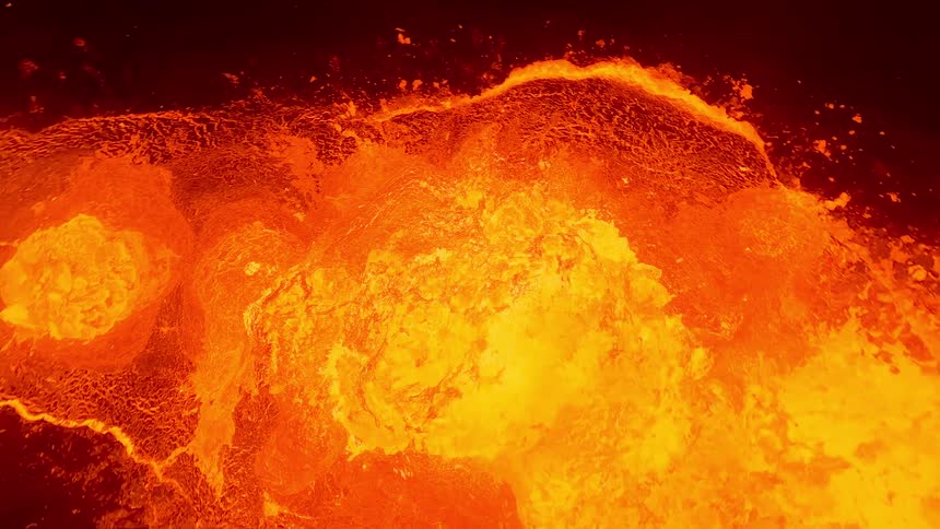 In the dark of night an glowing lava erupts from a volcano
