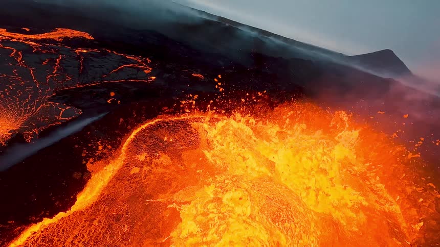 A volcanic eruption at sunset with lava flowing violently down the mountains slopes