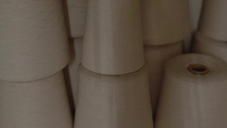 Lightcolored yarn cones stacked side by side in a textile production setting