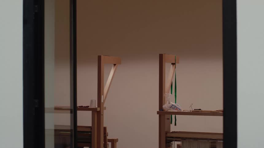 Measuring tape hangs from part of a wooden frame indoors