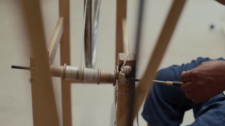 The man is spinning thread on the wheel