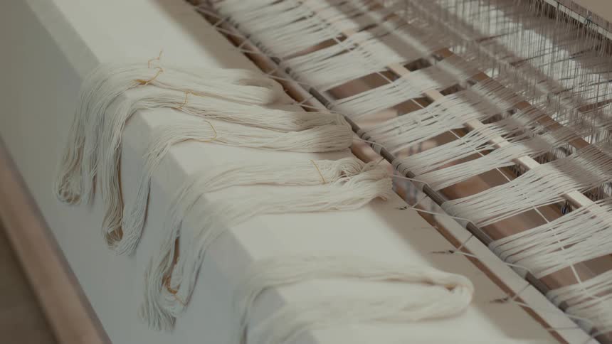 Light comes on shining onto the threads of a floor loom