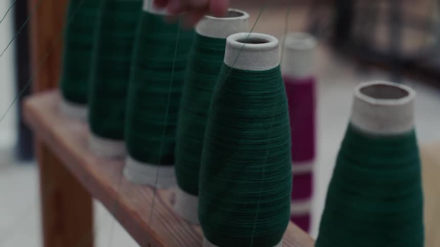 Woman adjusts thread cones in a weavers workshop