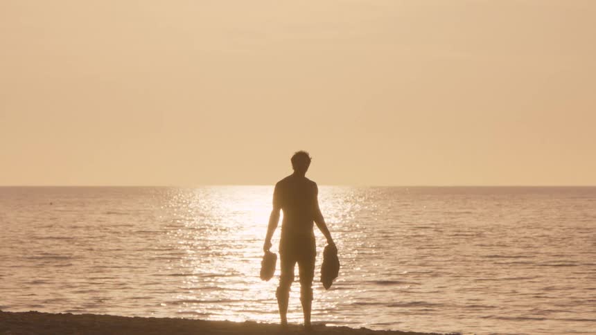 The man watches the sunrise on the beach