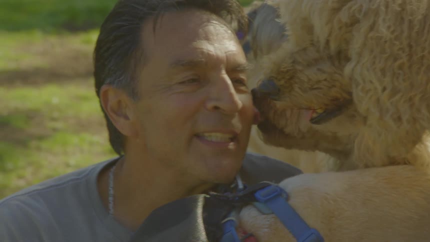 A man getting licked by dogs outdoors