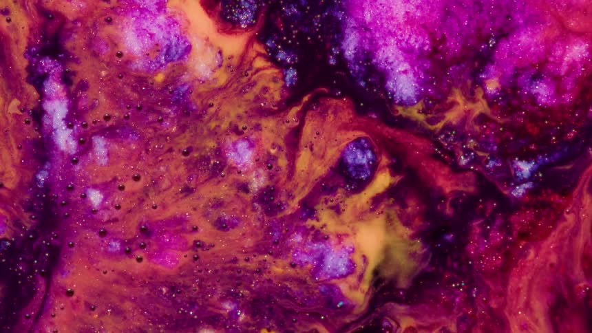 Vibrant purple pink and yellow fluids swirl together in a macro shot creating organic patterns as dark bubbles and fine glitter drift through the shifting textures of the viscous mixture