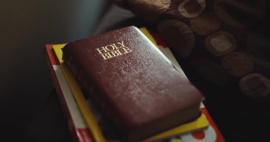 Leather bound bible over other publications in a room indoors during day time