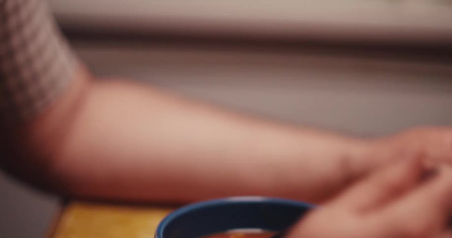 A man eats soup from a blue bowl
