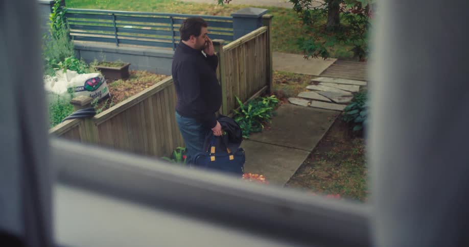 Man with a suitcase in the backyard of a house