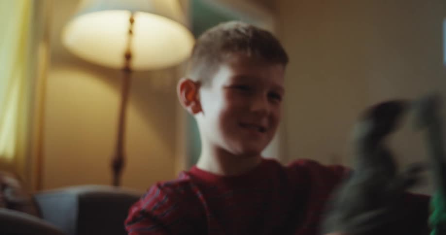A young boy happily plays with toy dinosaurs on a colorful rug