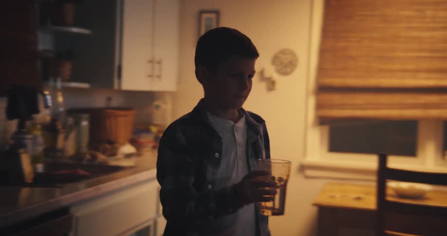 Boy in the kitchen washing a glass and serving a plate of food