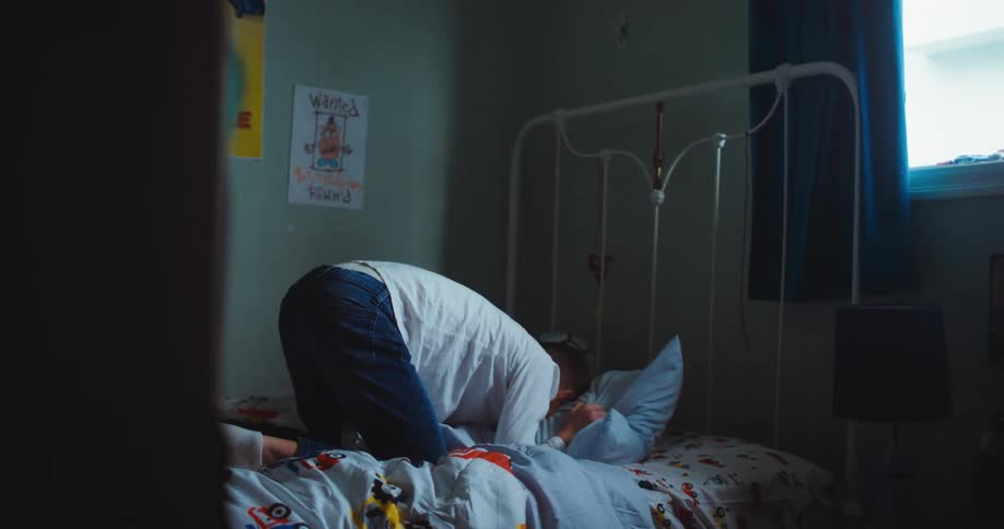 A young boy jumps onto his bed punches his pillow and then lets out a frustrated shout