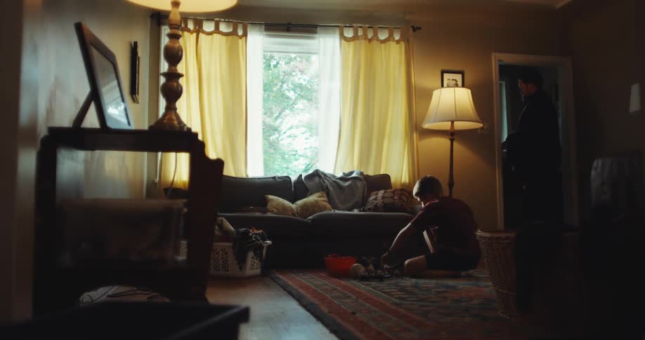 A father walking out of a room with his son playing